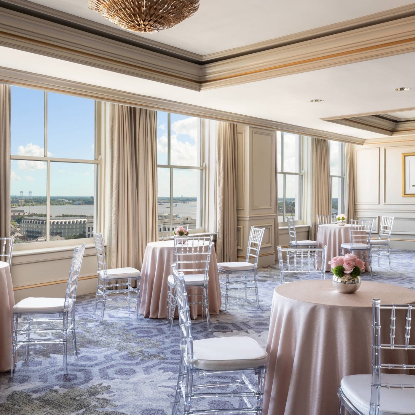 Event space at The Ritz-Carlton, New Orleans, set with cocktail tables, with windows over the Mississippi River