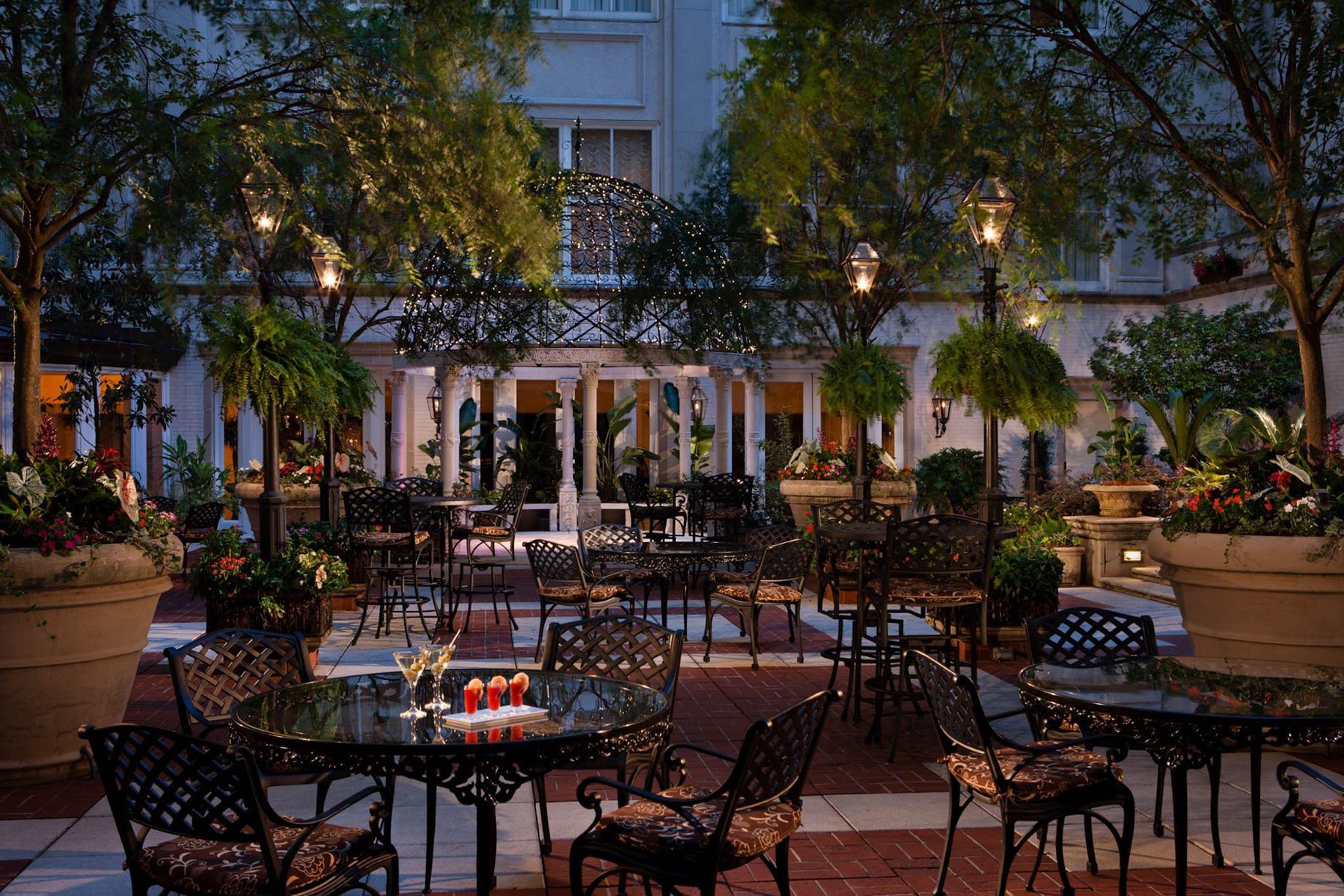 Courtyard at The Ritz-Carlton, New Orleans in the evening, with tables and gas lanterns